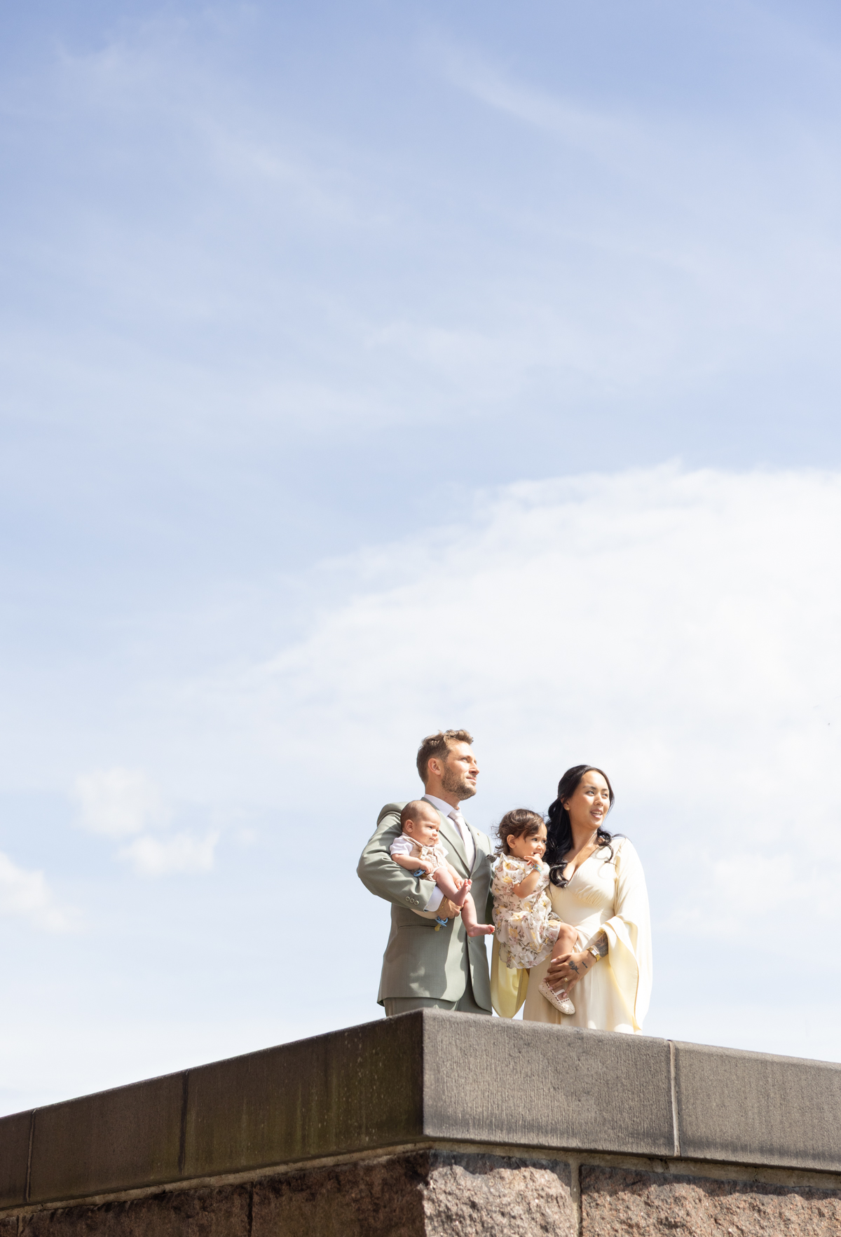 Familjen står tillsammans på en mur mot blå himmel