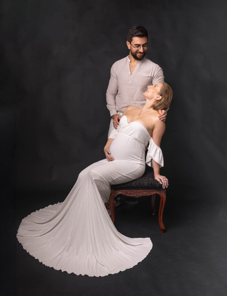 Gravidfotografering i studio, par pa en utsirad stol